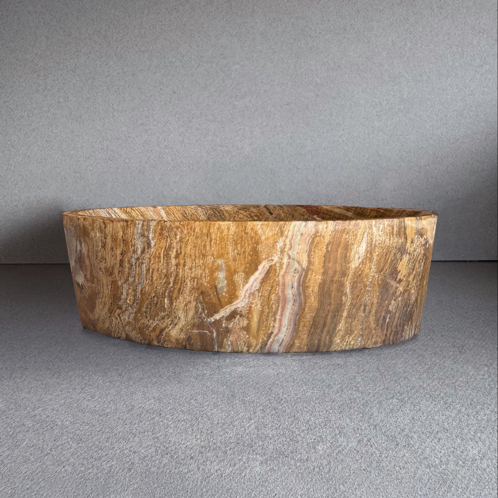 Hand-carved onyx bowl featuring rich golden, chestnut, and blush veining with a raw matte finish. Sculptural and one-of-a-kind, this natural stone vessel blends organic texture with minimalist design—ideal as a fruit bowl, altar dish, or decorative centerpiece. Crafted sustainably with no polish or synthetic materials.

