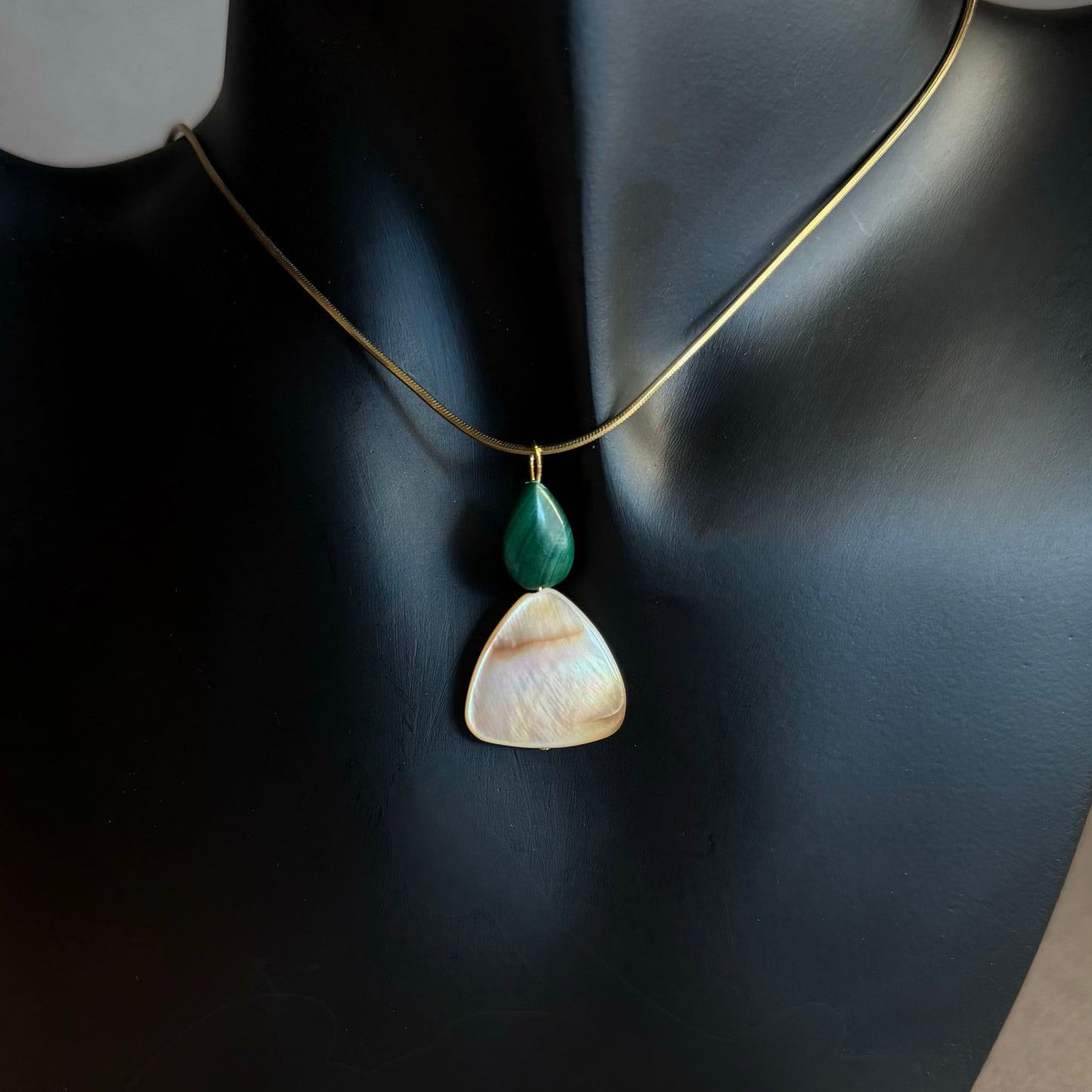 gold snake chain herringbone necklace with a malachite mother of pearl pendant Necklace with two pendant stones on a black background