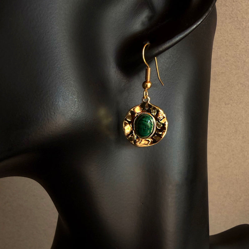Handmade malachite gold medallion dangle earring worn on black sculptural bust, featuring deep green stone and hammered gold finish
