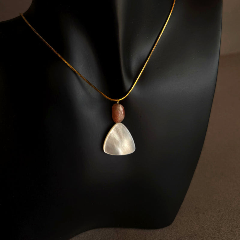 Mother of pearl and sunstone pendant necklace on gold waterproof snake chain displayed on black bust
 Necklace with a pendant on a black mannequin