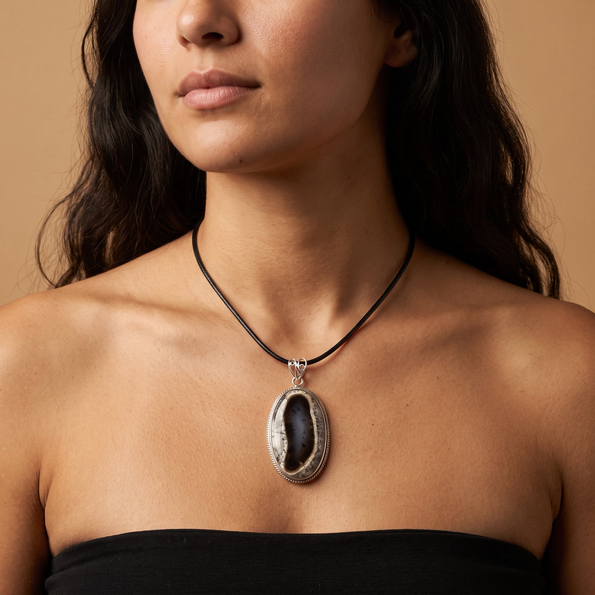 Dendritic agate oval pendant on a short black cord, worn high below the collarbone with a black strapless top; blue-gray center with black branching dendrites inside a chalky white rim, sterling silver rope-edge bezel and openwork bail