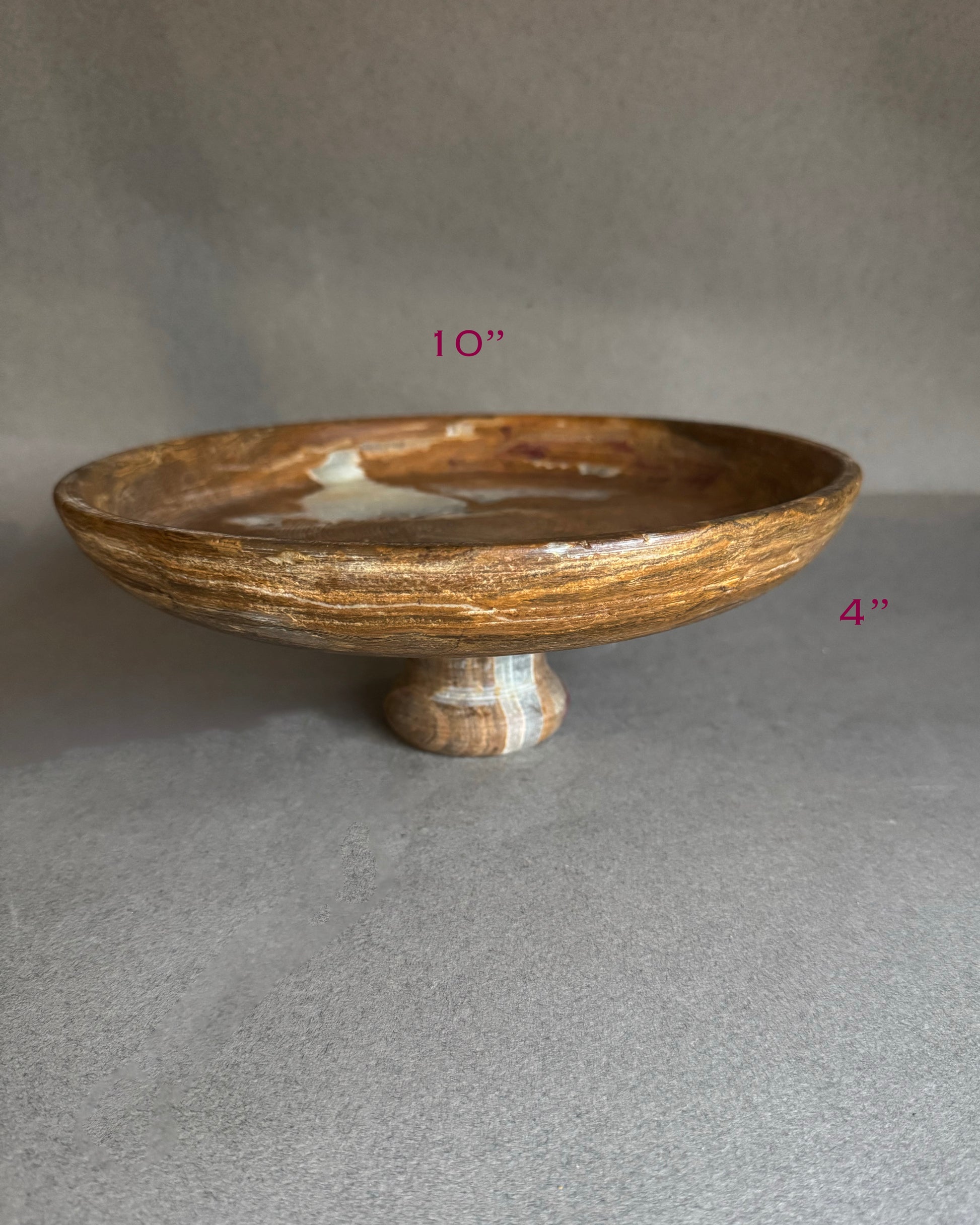 Angled view of cream and honey onyx pedestal bowl, sculptural stone decor piece for dining table, kitchen island, or jewelry catchall.
