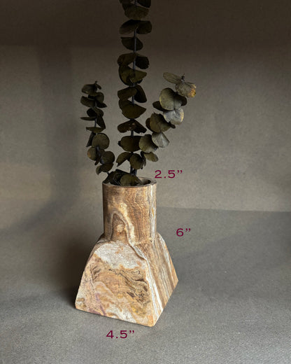 Decorative stone vase with a plant on a gray background