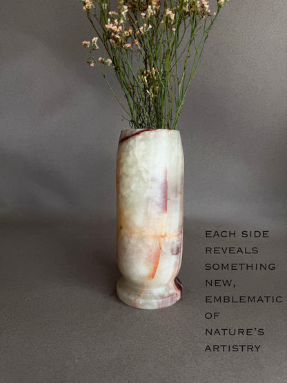 Decorative onyx natural stone vase with dried flowers on a gray background