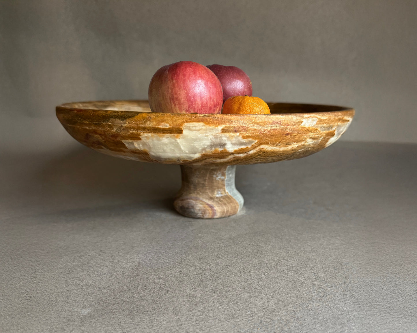 Side profile of brown onyx pedestal bowl with cream banding, handmade natural stone fruit bowl and catchall dish for organic modern decor.
