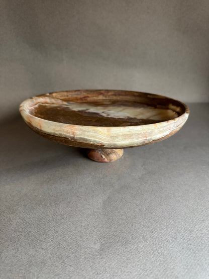 Wooden pedestal dish on a gray surface with a neutral background