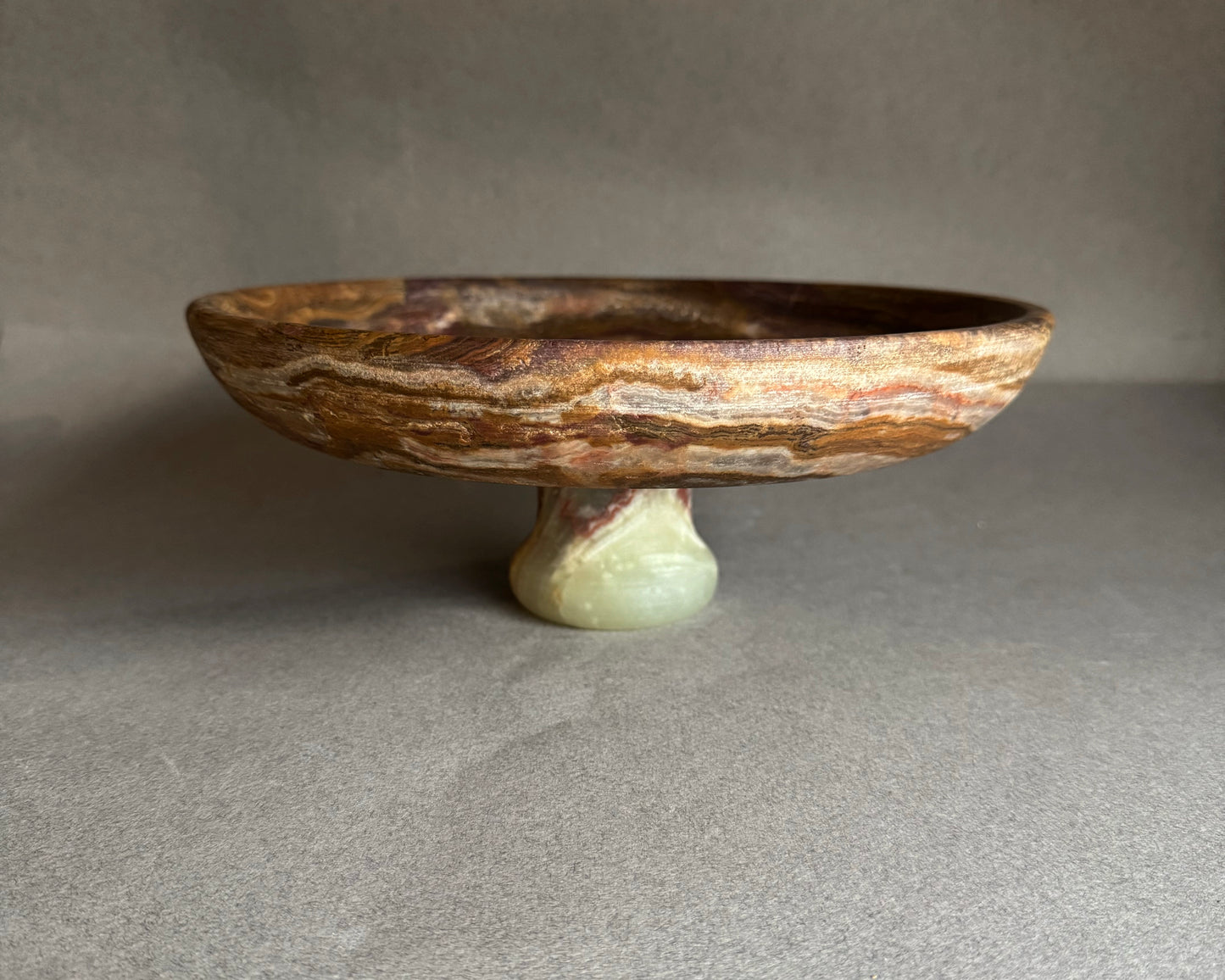Decorative stone bowl on a stand against a neutral background
