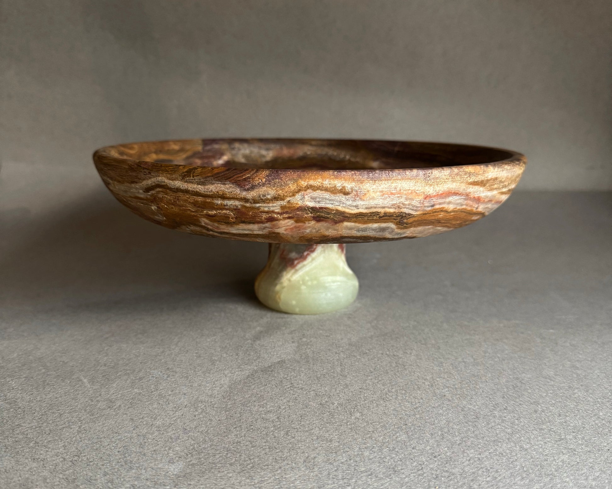 Decorative stone bowl on a stand against a neutral background