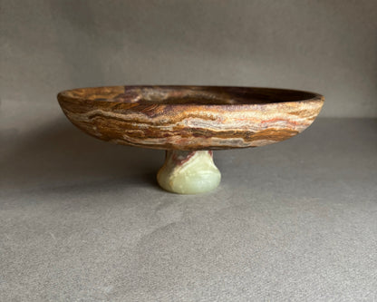 Decorative stone bowl on a stand against a neutral background