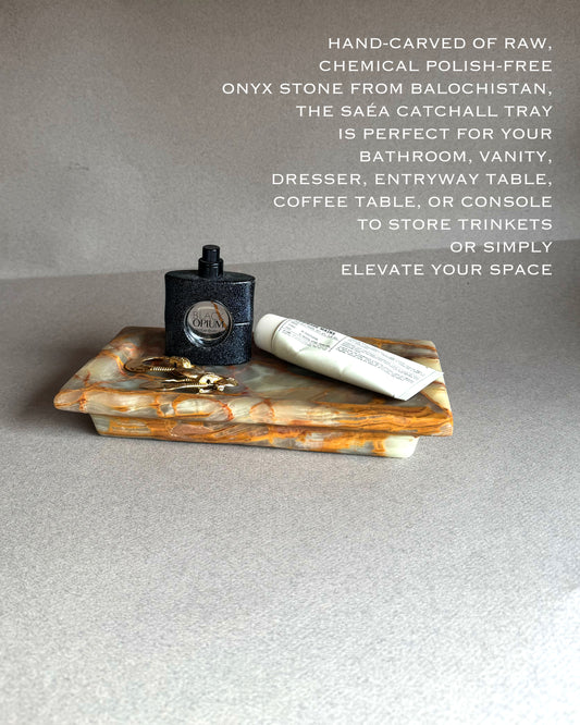 Onyx catchall tray with a bottle and tube of cream on a gray surface, text describing the product.