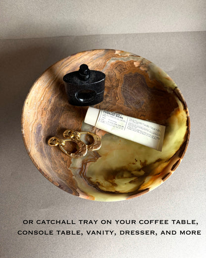 Decorative onyx stone catchall tray with a black container and gold jewelry on a neutral background