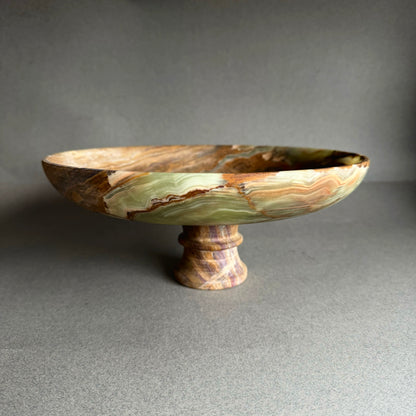 Decorative onyx bowl with a pedestal base on a gray background