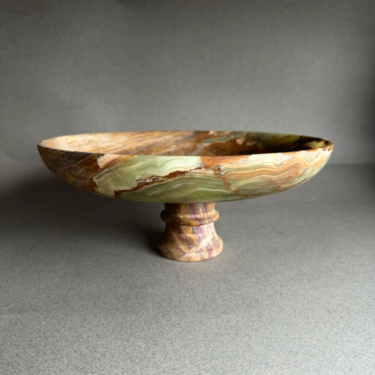 Decorative onyx bowl with a pedestal base on a gray background