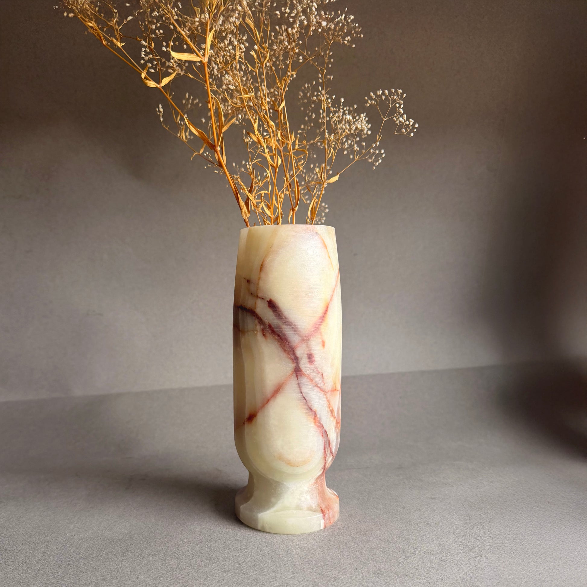Marble-patterned vase with dried branches on a gray background