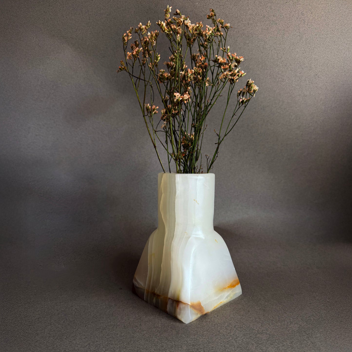 White marble vase with brown streaks holding dried flowers on a gray background white onyx vase 