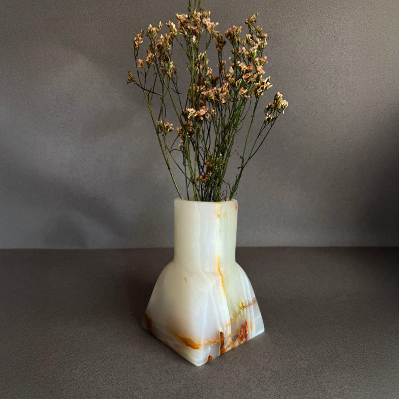 Decorative white onyx vase with dried flowers on a gray background