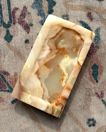 Decorative onyx stone tray with a unique pattern on a textured surface