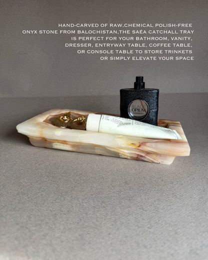 Onyx stone catchall tray with a bottle and tube of cream on a gray surface.
