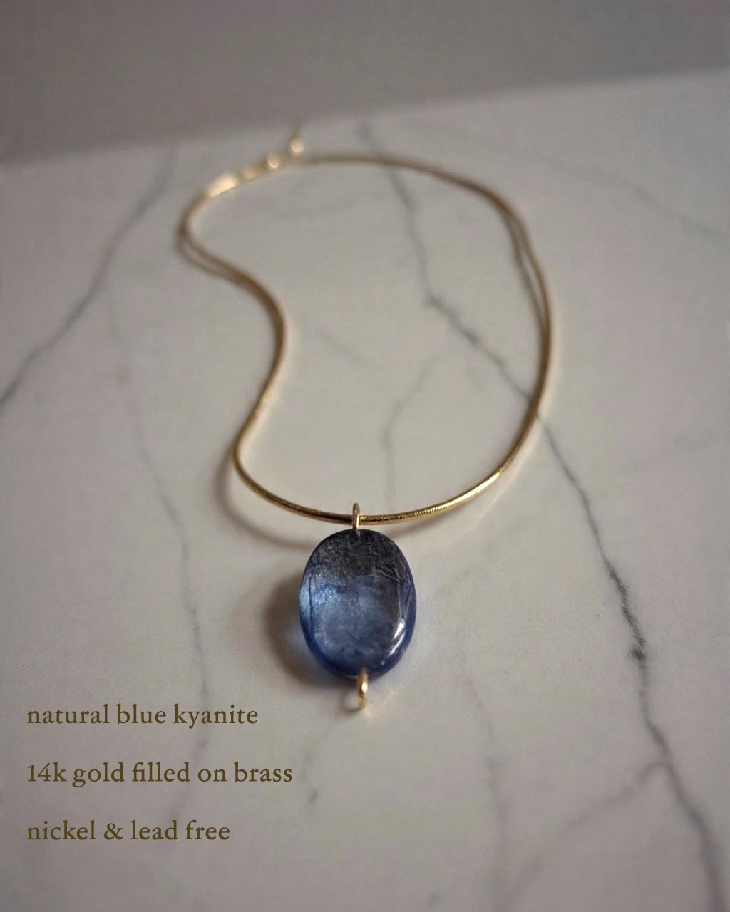 Natural blue kyanite stone pendant with vertical crystalline texture, 0.5 by 1 inch, set in sculptural gold bezel on 14k gold-filled chain.
