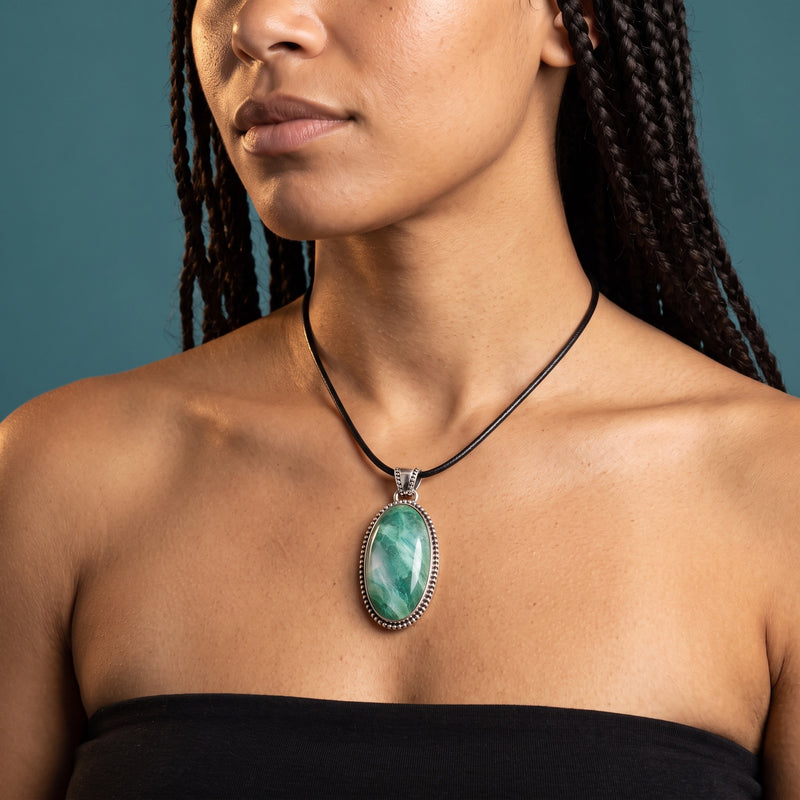 Sea-glass blue and white larimar oval pendant in a beaded sterling silver bezel on a short black cord, worn at the collarbone