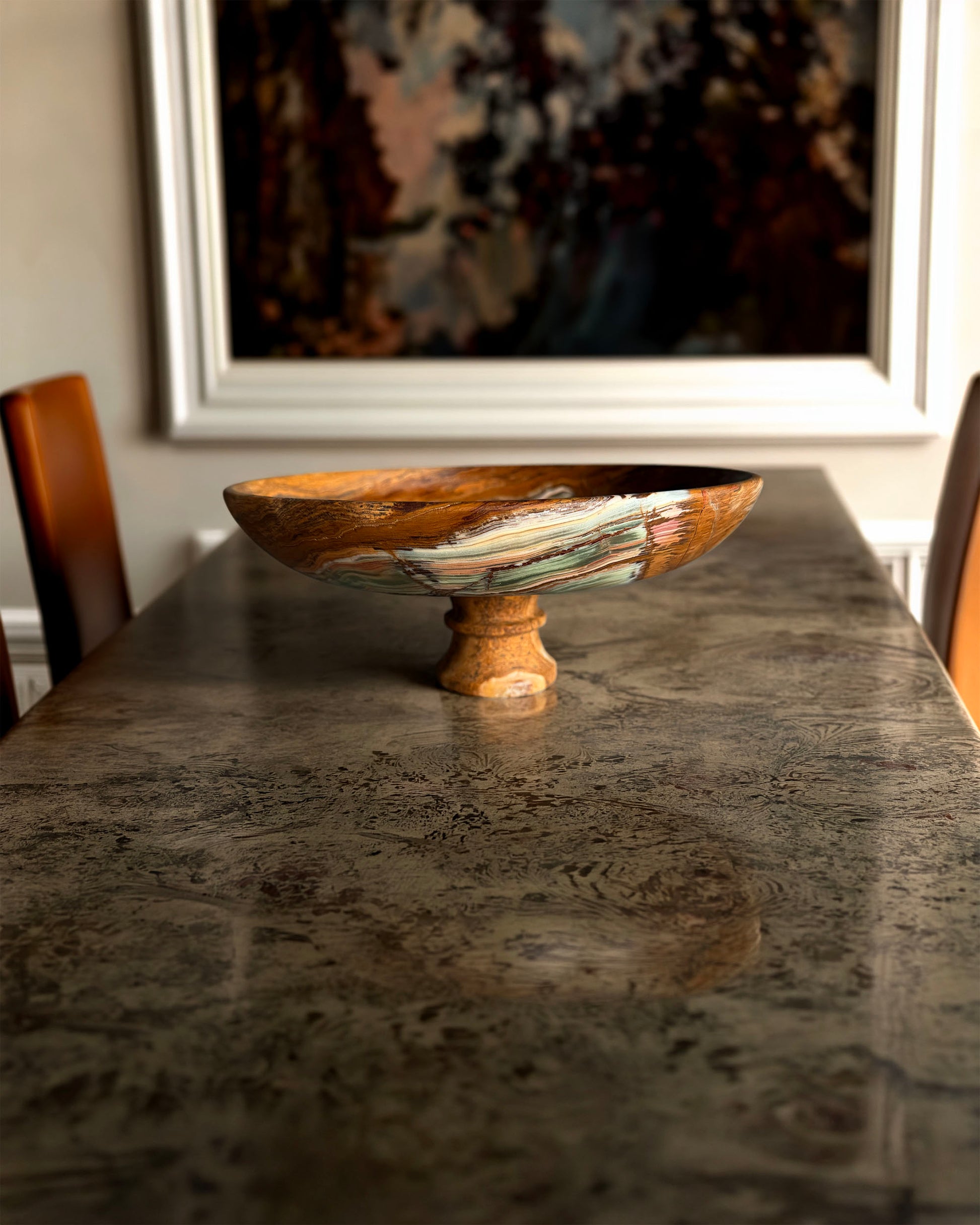 onyx pedestal bowl bowl with a pedestal base on a dark stone table, framed artwork in the background