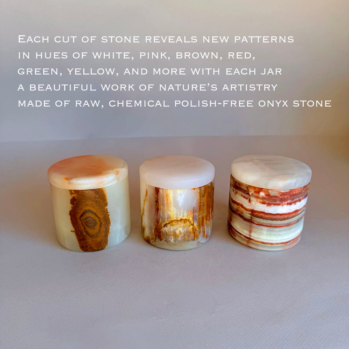 Three onyx stone jars with lids with natural patterns on a light background