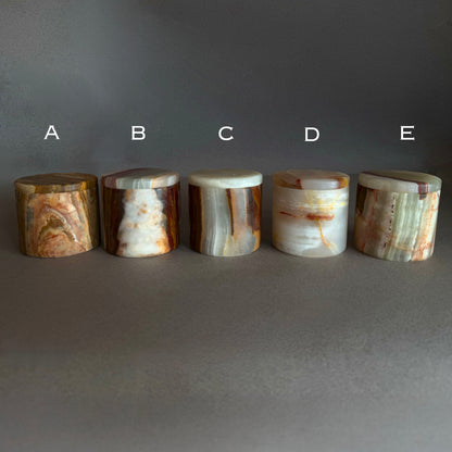 Five cylindrical agate stone jars labeled A to E on a gray background