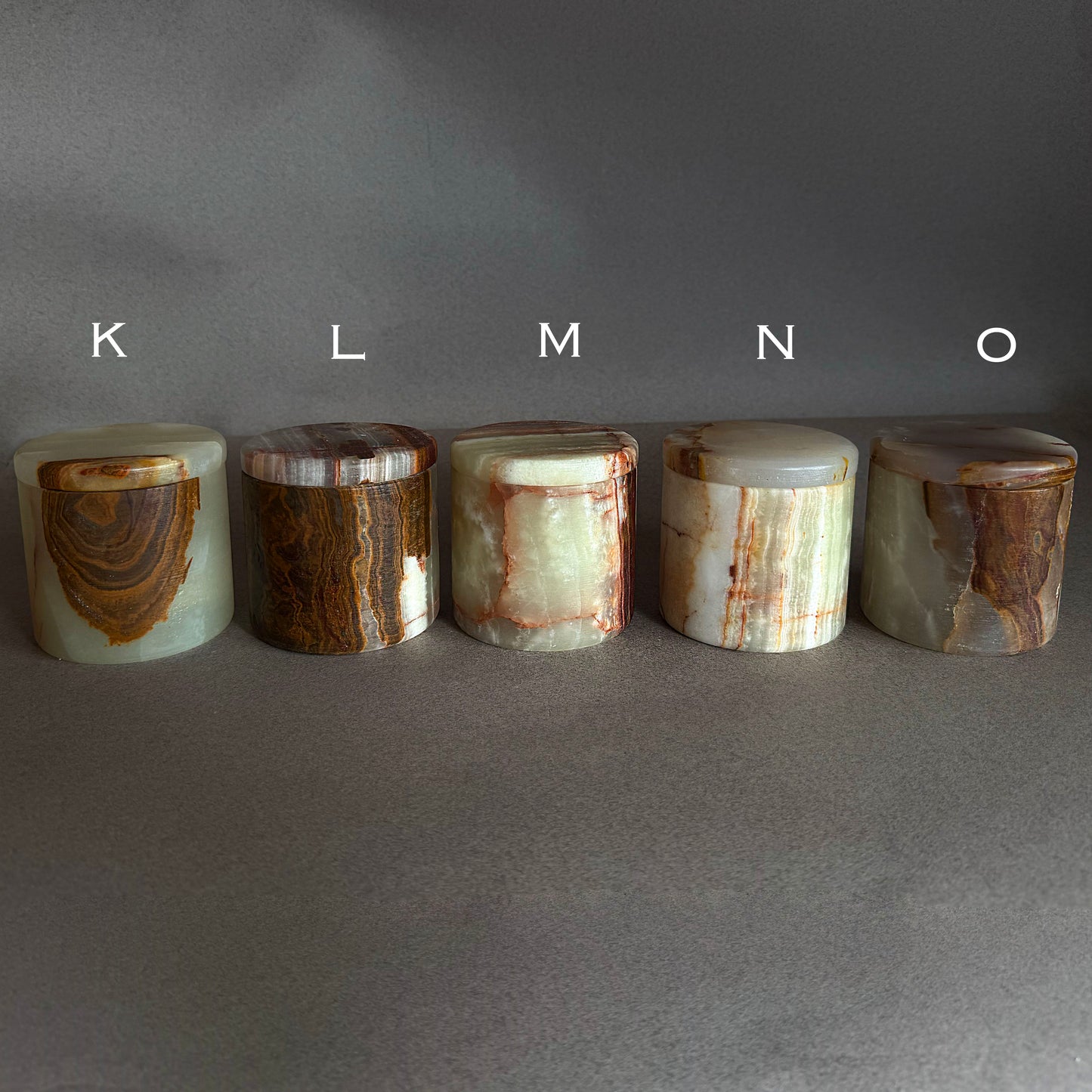 Five cylindrical stone objects with varying patterns on a gray background