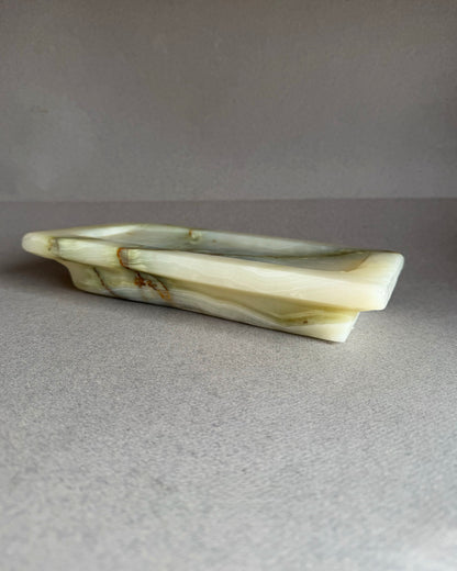 White green onyx stone catchall tray with green veins on a gray background
