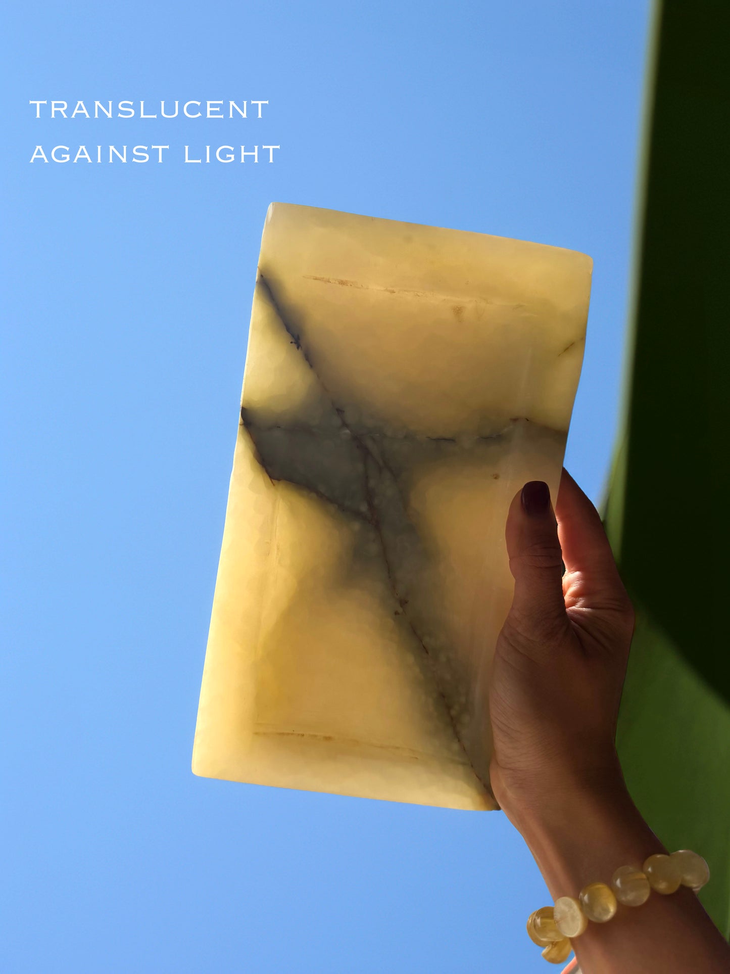 Hand holding a translucent stone tray against a blue sky
