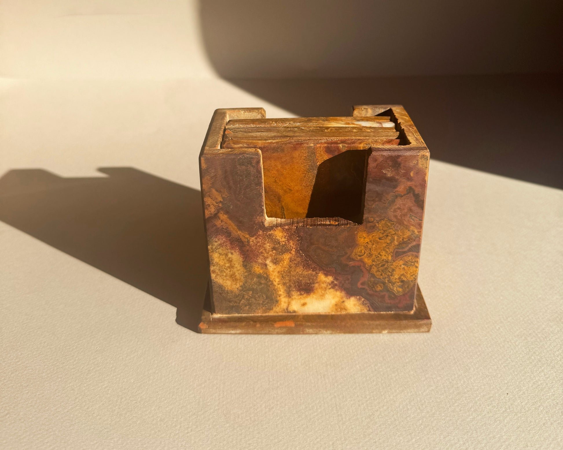 Rust-colored square coaster holder set on a beige surface