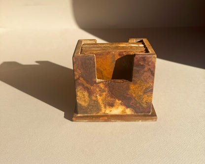 Rust-colored square coaster holder set on a beige surface