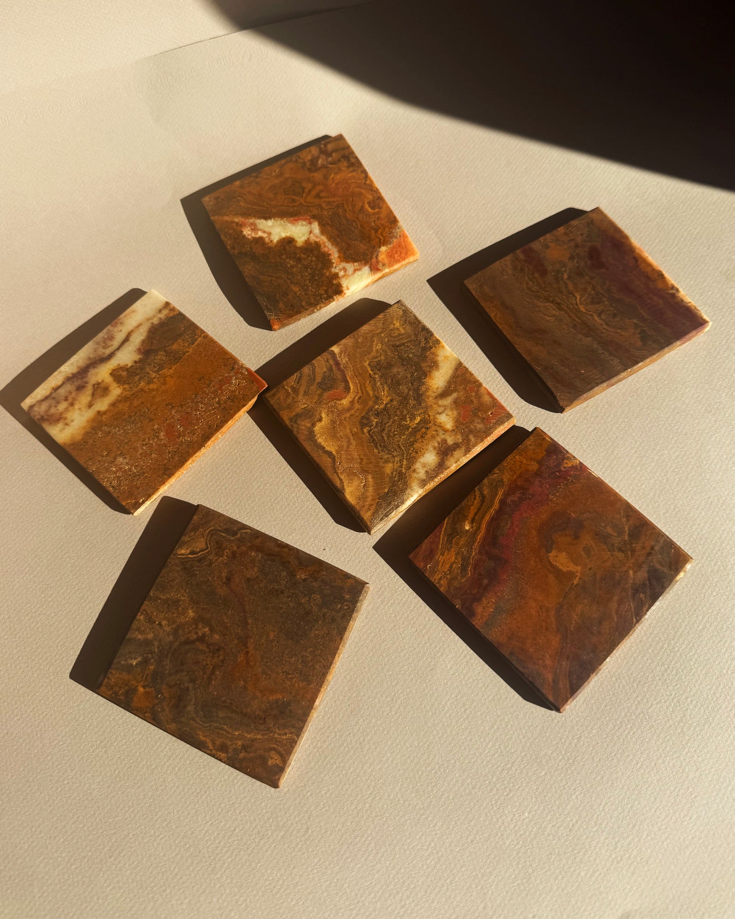 Brown square coasters with marbled pattern on a light gray surface