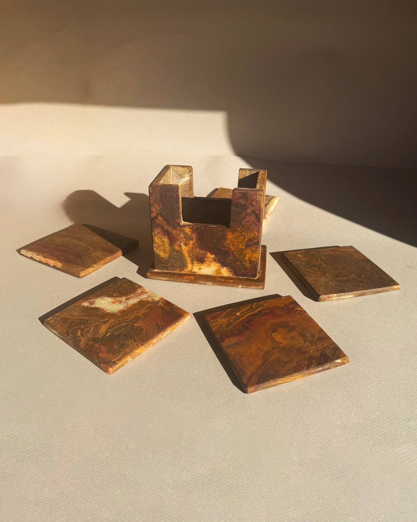 Set of bronze-colored square coasters on a light surface with a dark background