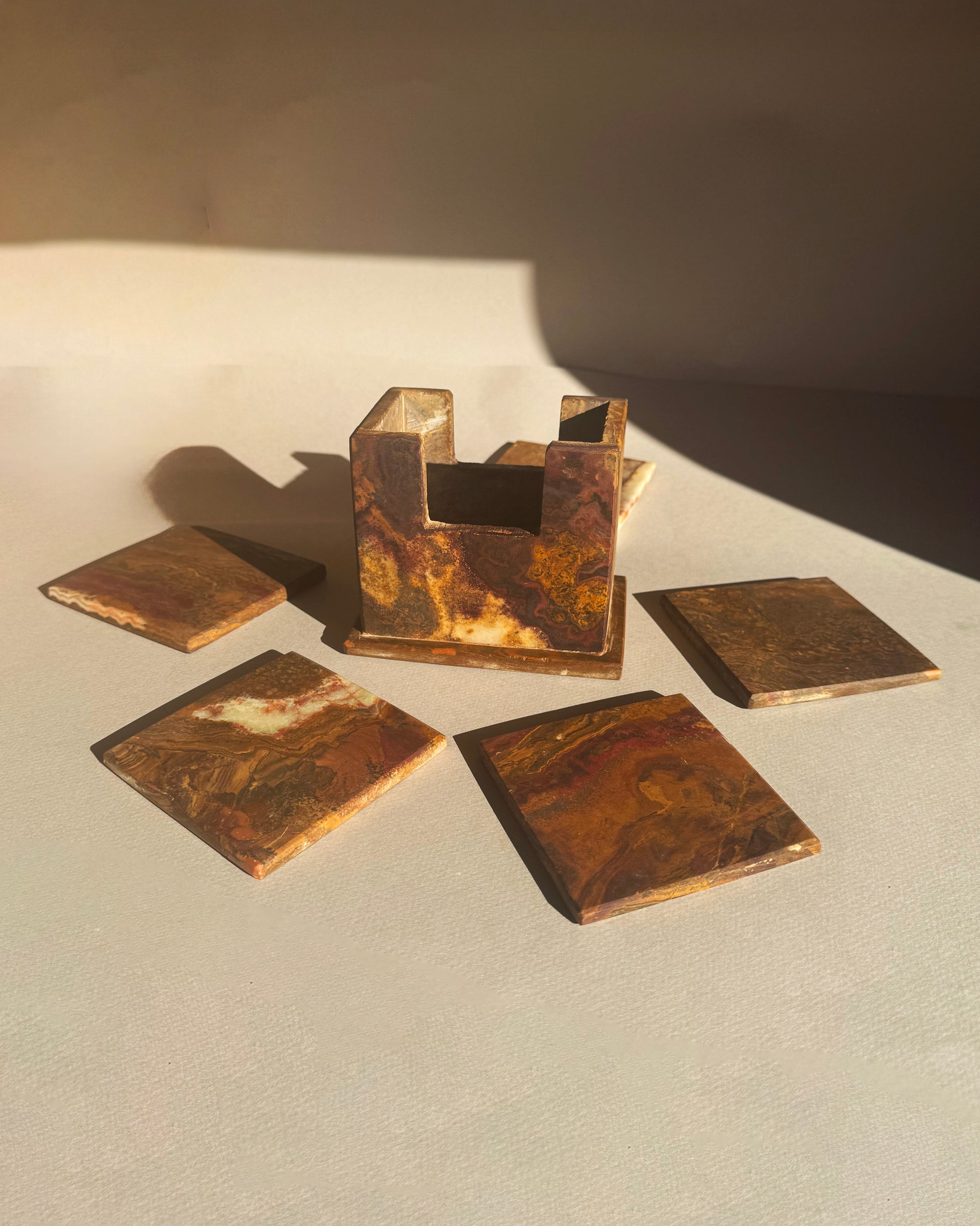 Set of bronze-colored square coasters on a light surface with a dark background