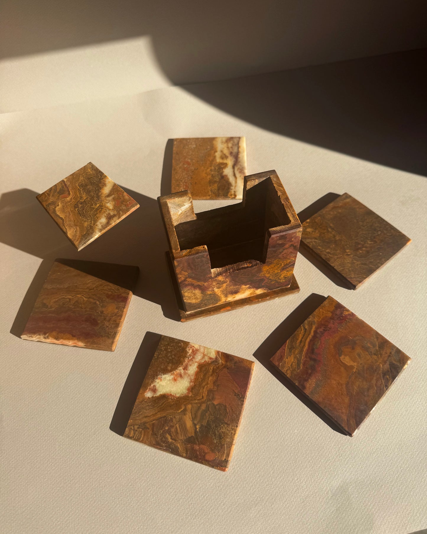 Set of bronze square coasters on a textured surface