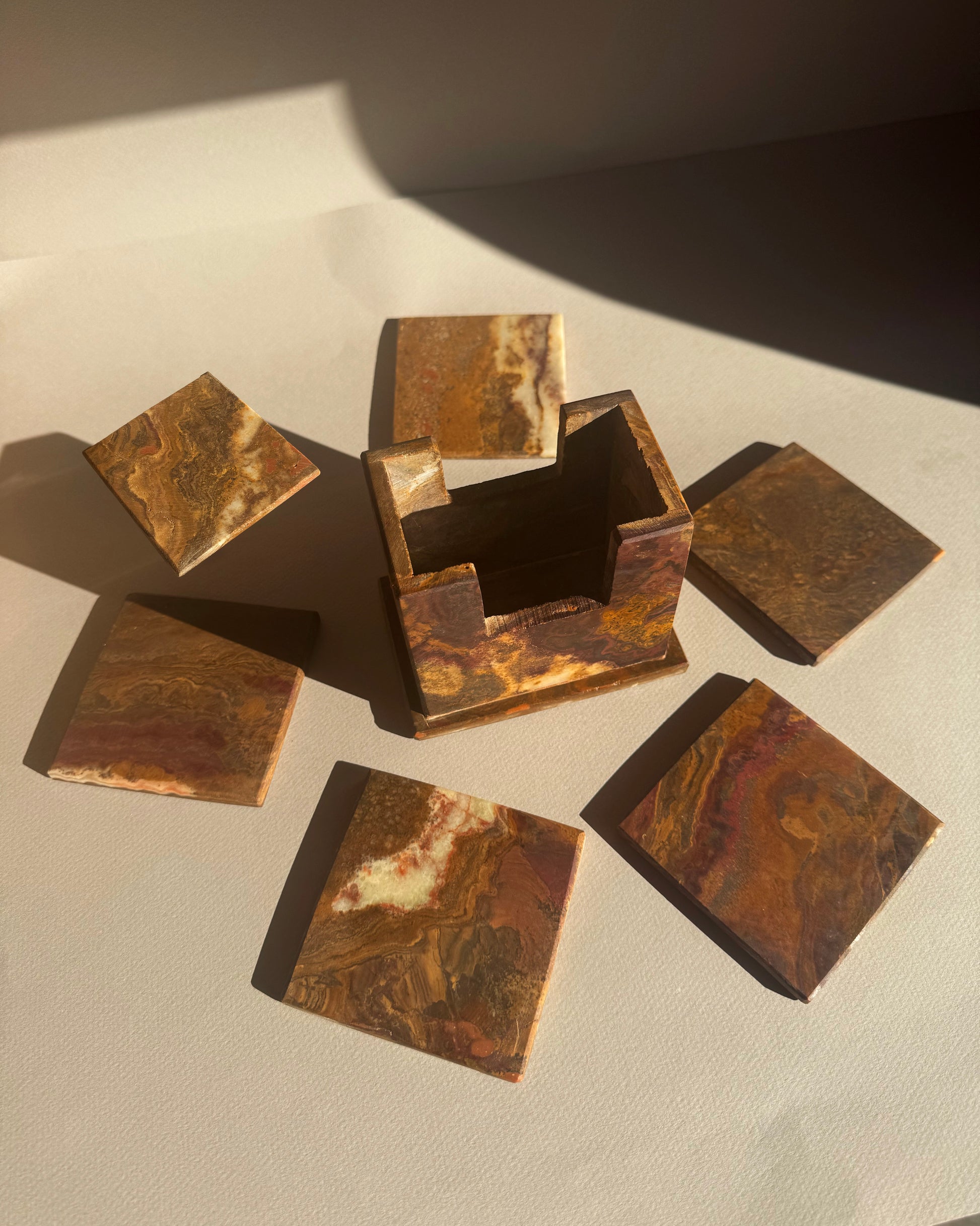 Set of bronze square coasters on a textured surface