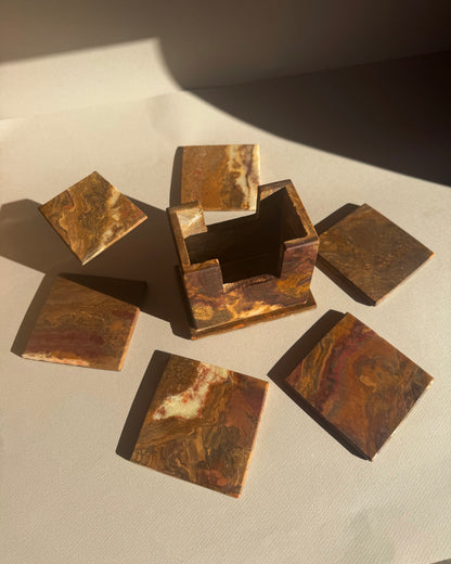Set of bronze square coasters on a textured surface