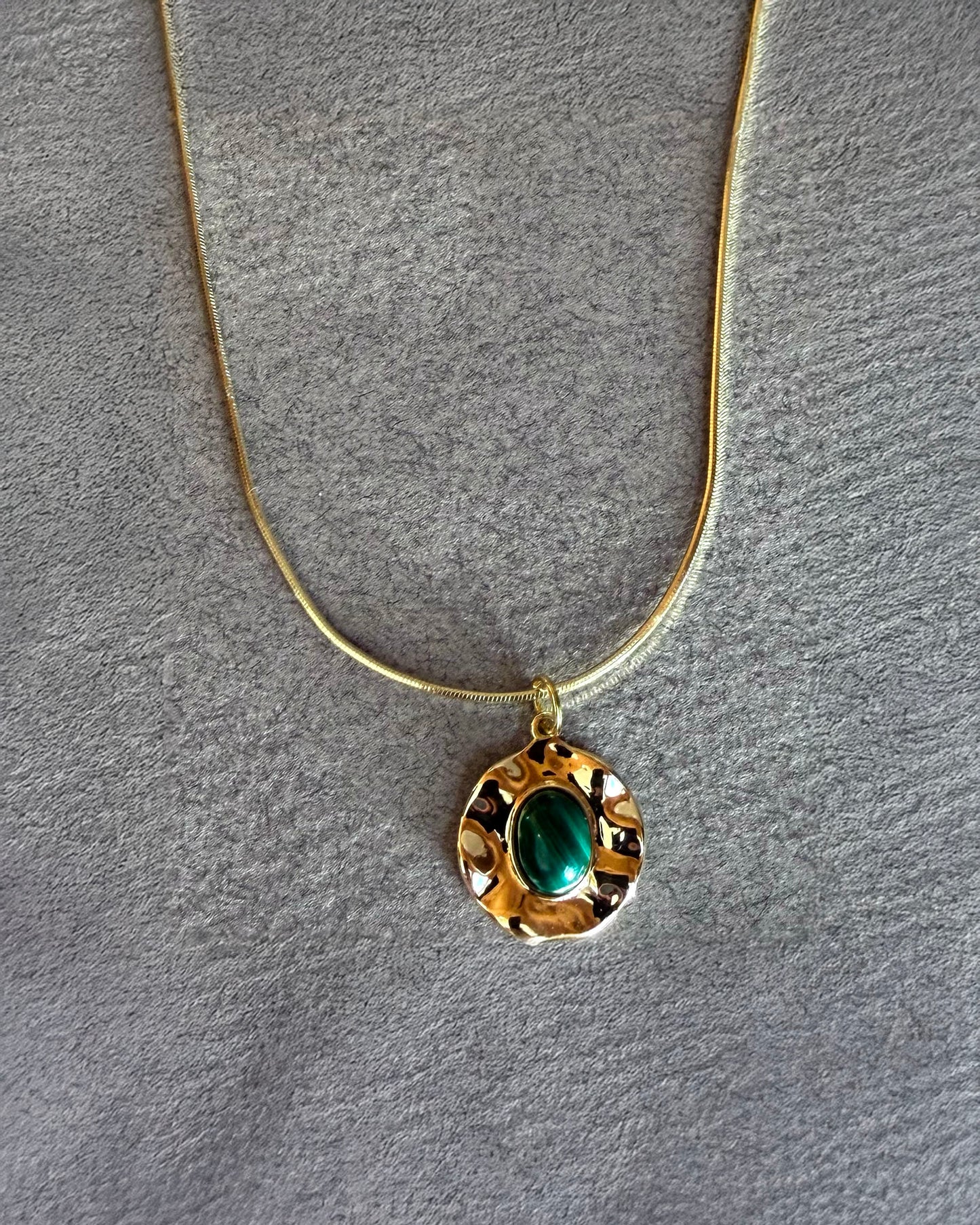 Handmade malachite medallion necklace on gold filled snake chain styled on black jewelry bust
