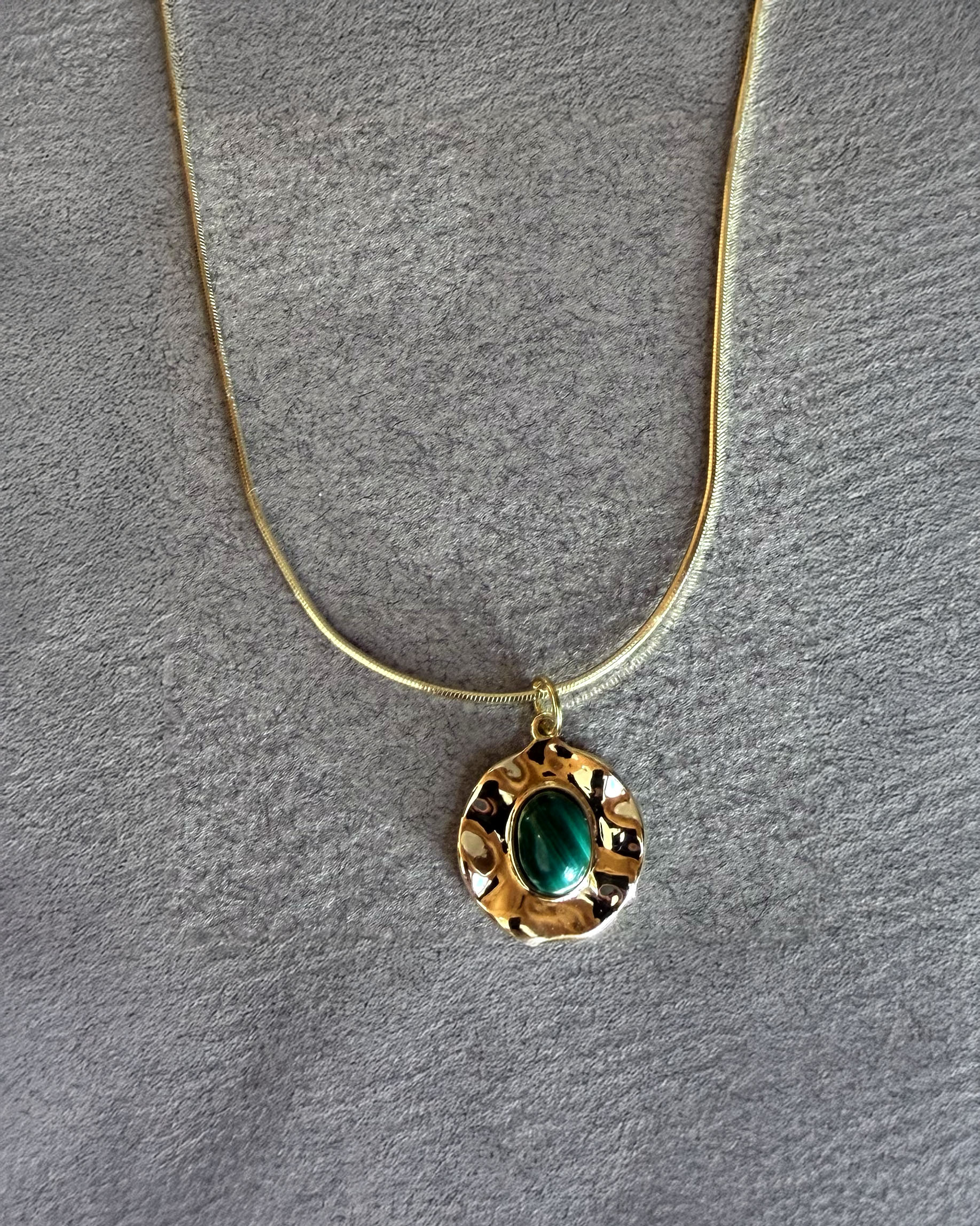 Handmade malachite medallion necklace on gold filled snake chain styled on black jewelry bust
