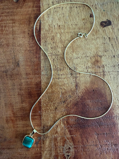 Silver necklace with a blue pendant on a wooden surface