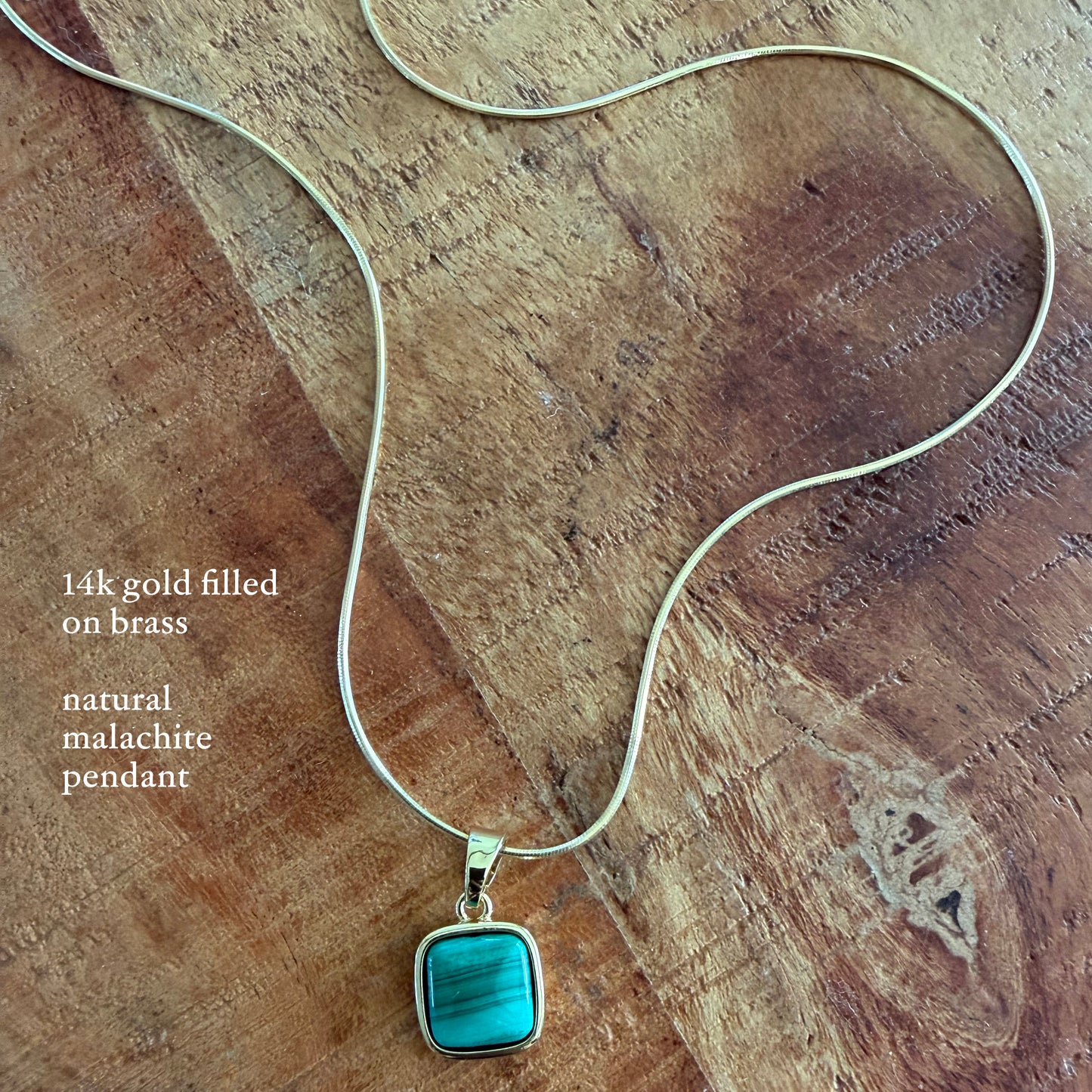 Necklace with a natural malachite pendant on a wooden surface