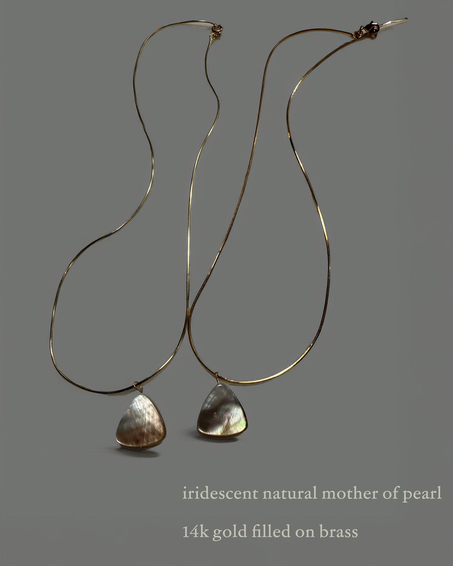 Pair of necklaces with iridescent natural mother of pearl drops on a gray background