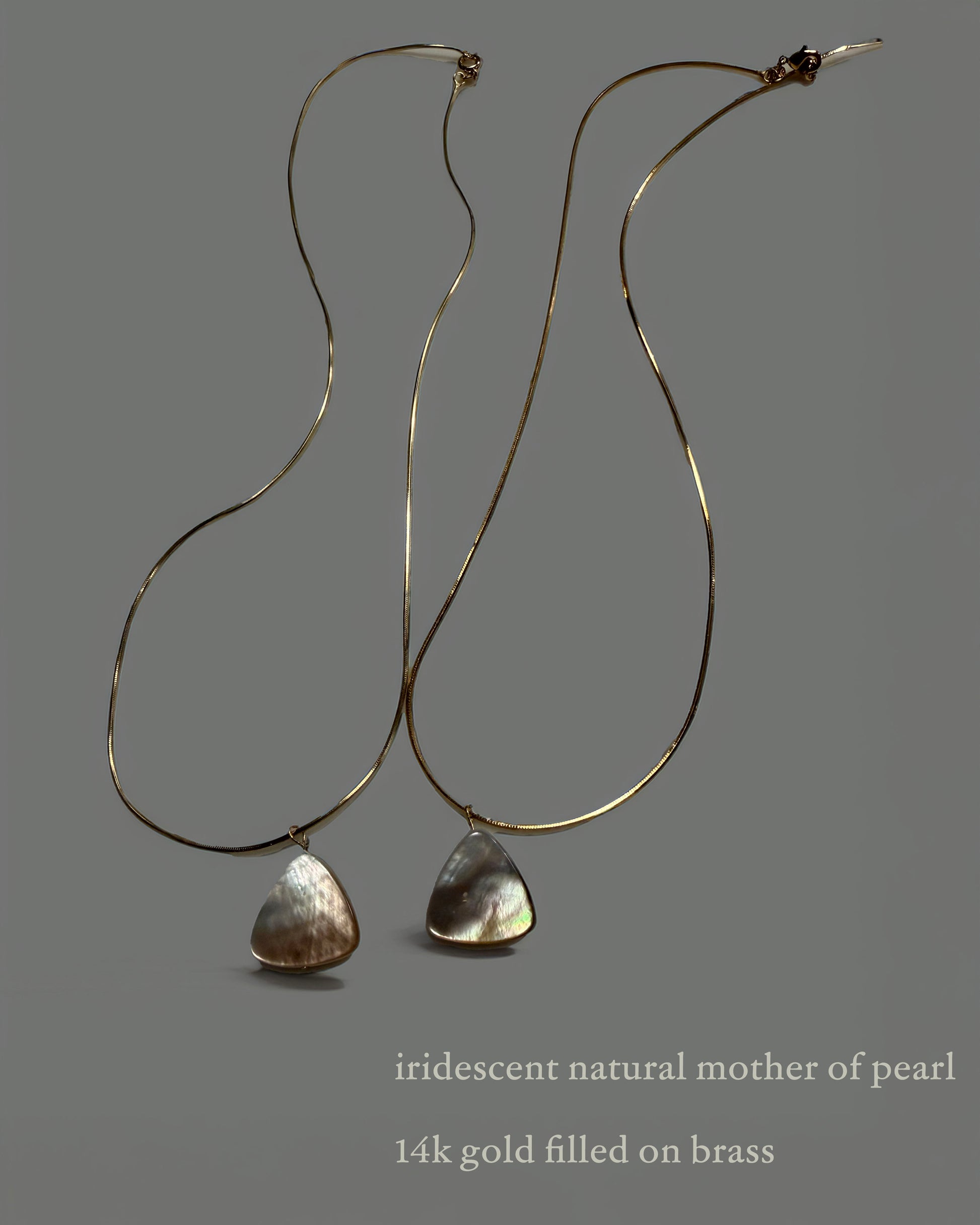 Pair of necklaces with iridescent natural mother of pearl drops on a gray background