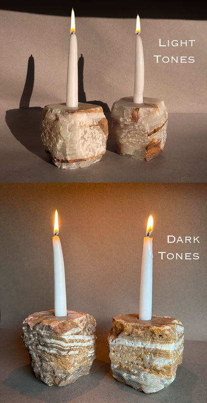 Two candle holders with candles, one labeled 'Light Tones' and the other 'Dark Tones', on a neutral background. Natural onyx candle holder set featuring light tonal variation with subtle translucency and raw stone finish
