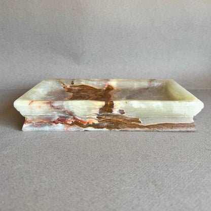 Front view of rectangular onyx tray with natural veining in cream, blush, and warm brown tones

