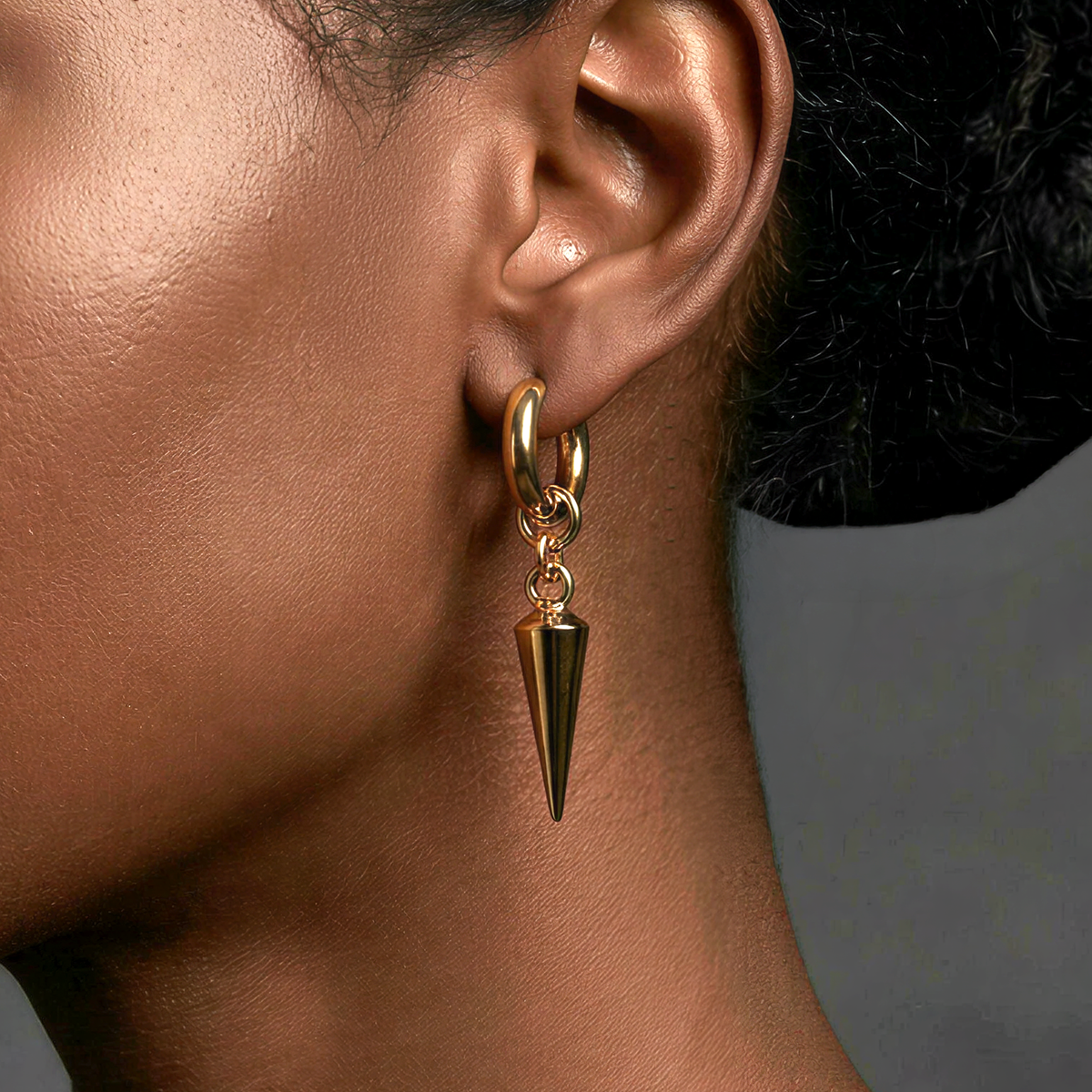 edgy Gold earring with a spike detail on an ear against a neutral background