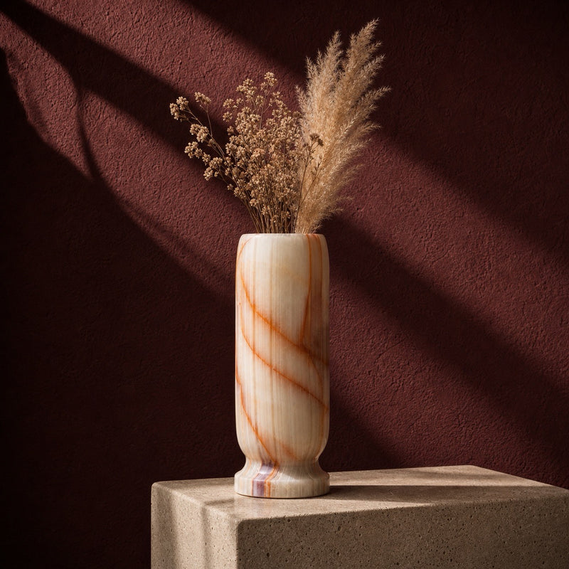 Cream and sienna hand-carved onyx bud vase on a stone pedestal, wide sienna seams crossing a cream field with a dark banded agate foot