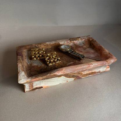 Decorative stone tray with decorative items on a gray surface