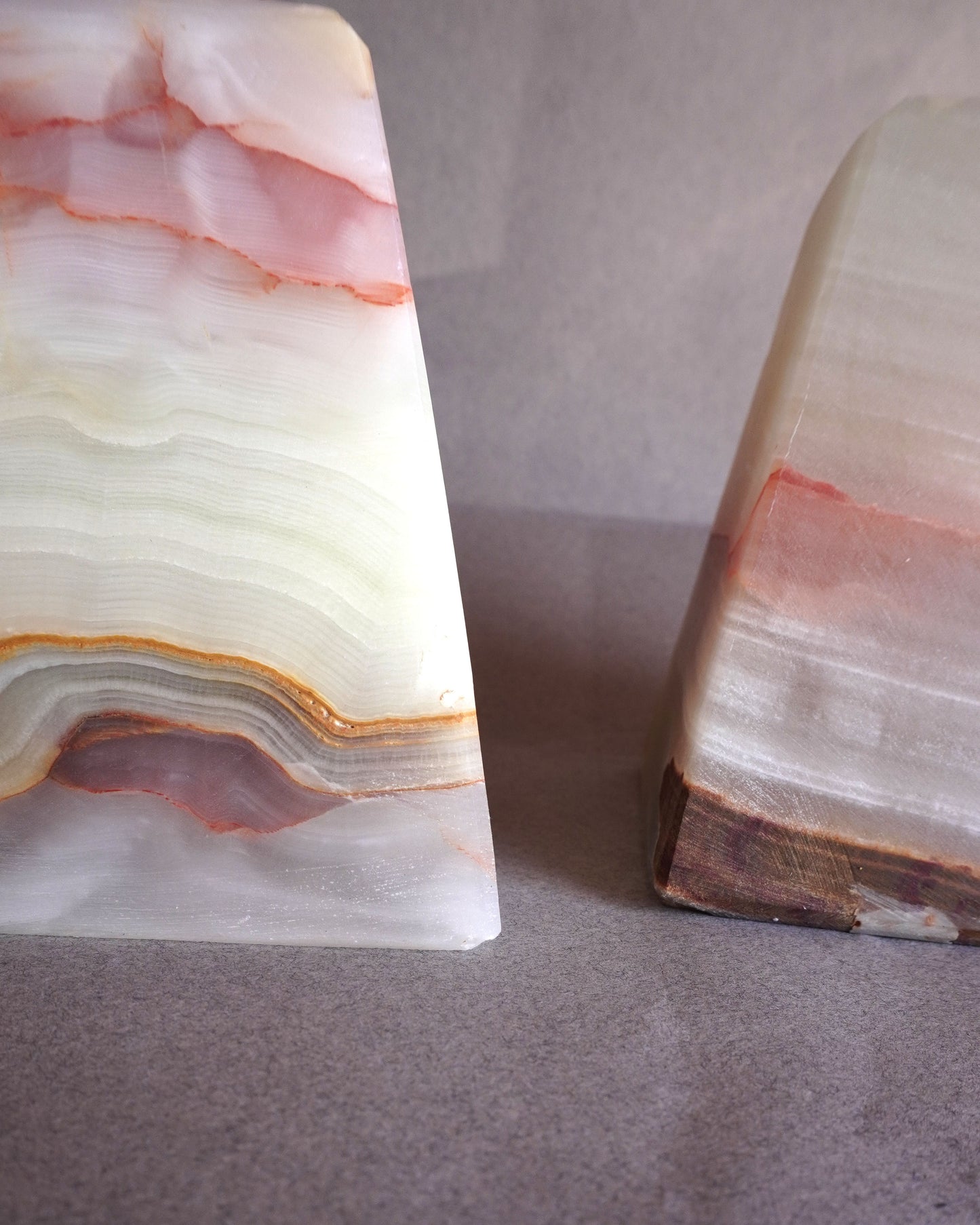 Two onyx stone bookends with a marbled pattern on a gray surface.